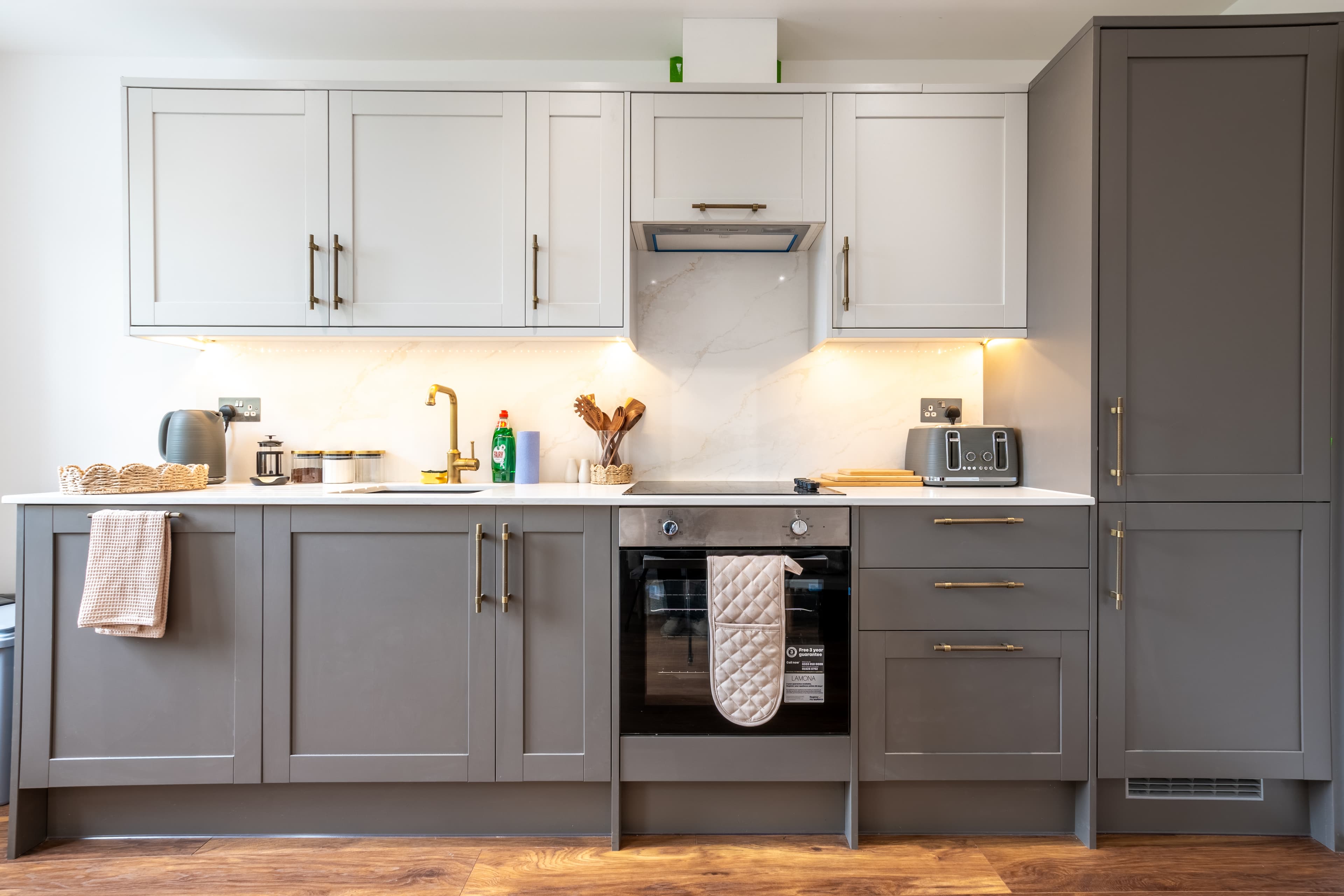 Sleek two-tone kitchen with quartz counters, lighting & built-in oven